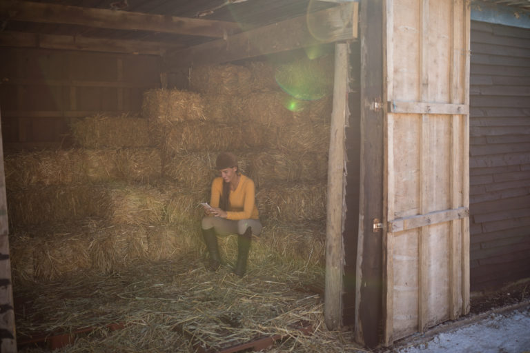 cell-phone-woman-hay-stack-barn-iStock-838110268-2400