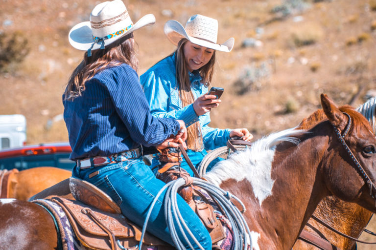 cell-phone-young-cowgirls-horseback-iStock-Azman-1146213086-1000