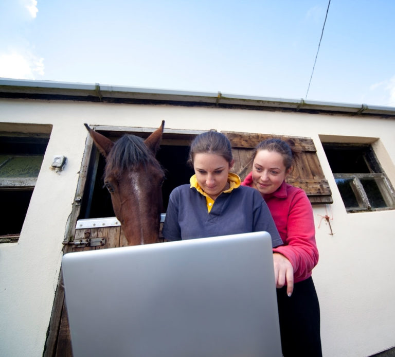 computer-two-young-women-horse-background-in-stall-iStock-Sasha-Fox-Walters-171152291-1000