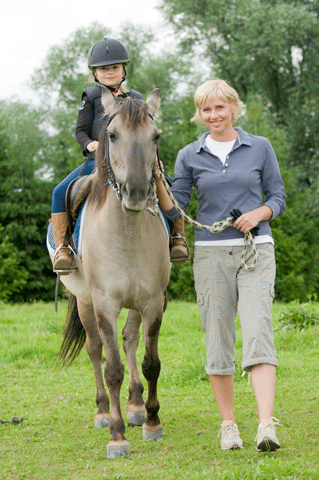woman leading pony with child