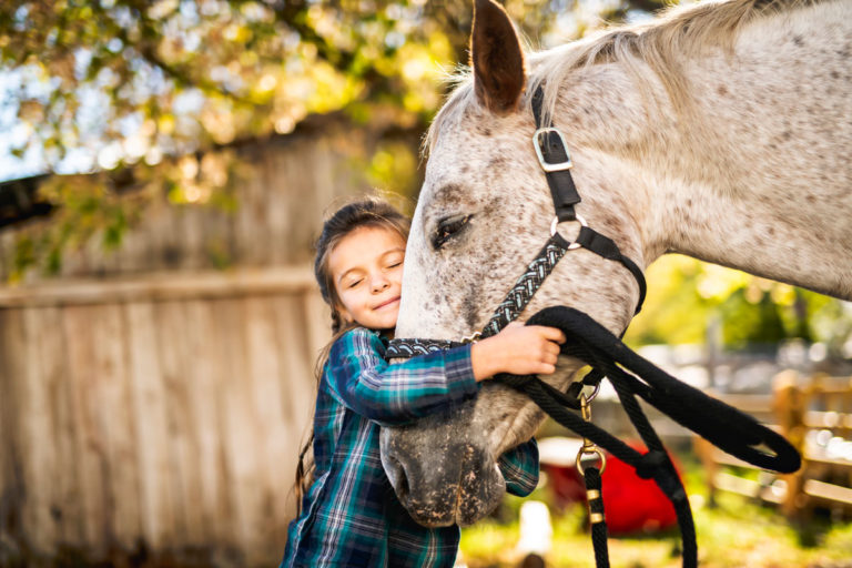 young-girl-hugging-horse-nose-Stock-LSO-Photo-1070002344-1200
